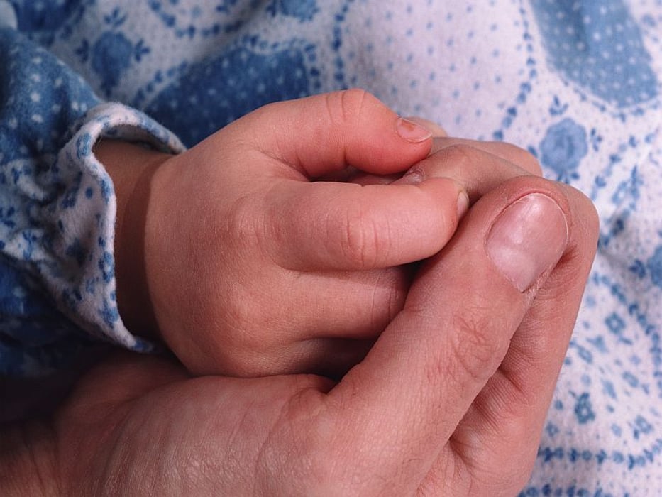 adult holding baby\'s hand