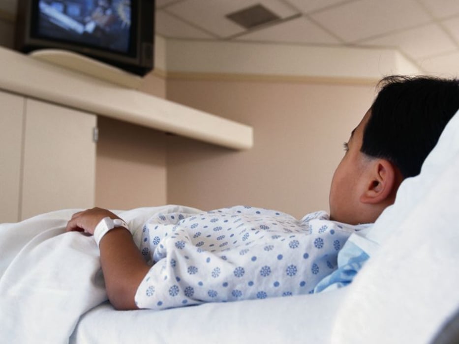 a boy watching TV on a hospital bed