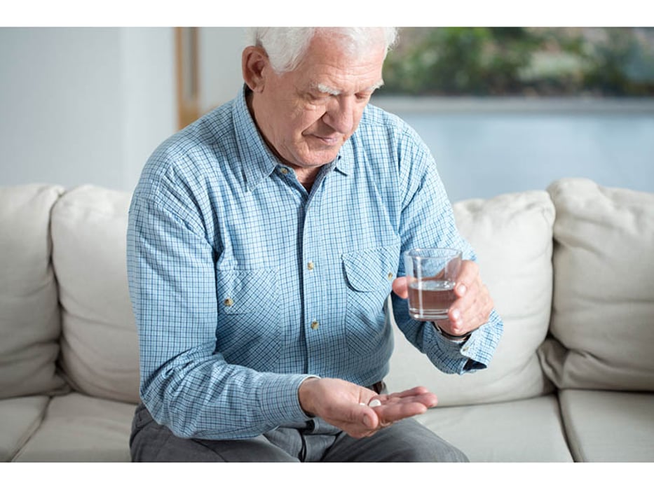 man sitting on the couch ready to swallow his pills