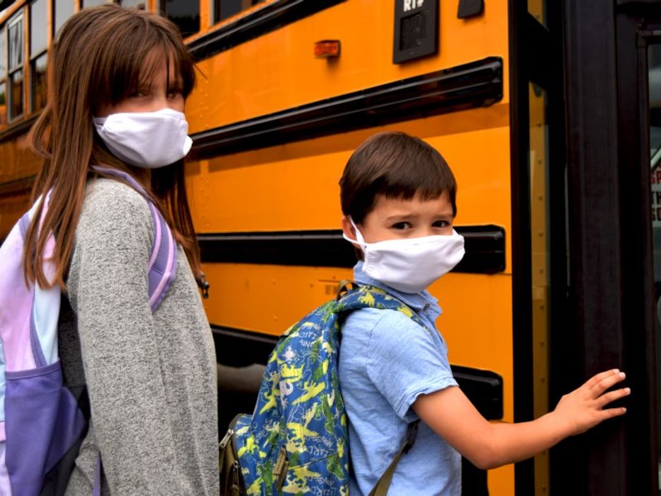 child wearing mask boarding school bus