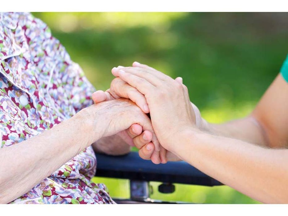 caregiver holding elderly person\'s hand