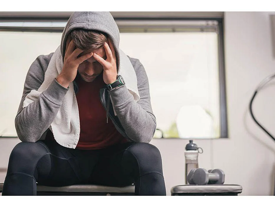 man looking depressed sitting in the gym