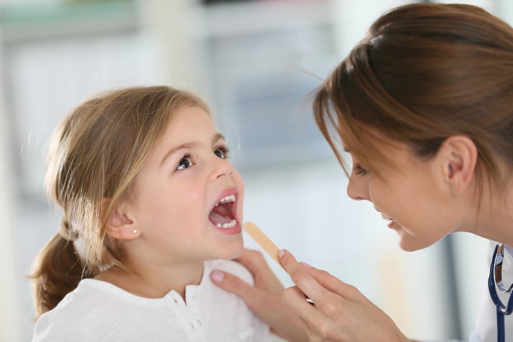 Doctor examining child's throat and mouth
