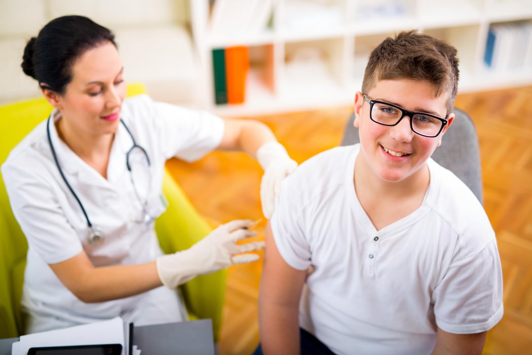 Teenage boy getting vaccination in his arm vaccine