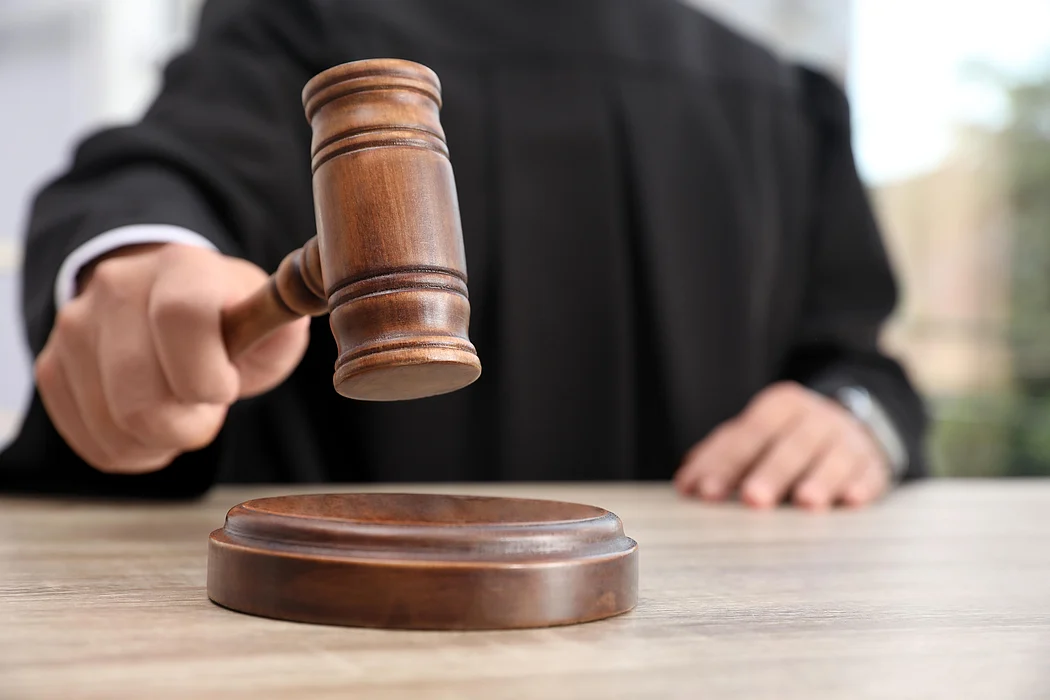 Judge with gavel at wooden table indoors, closeup. Criminal law