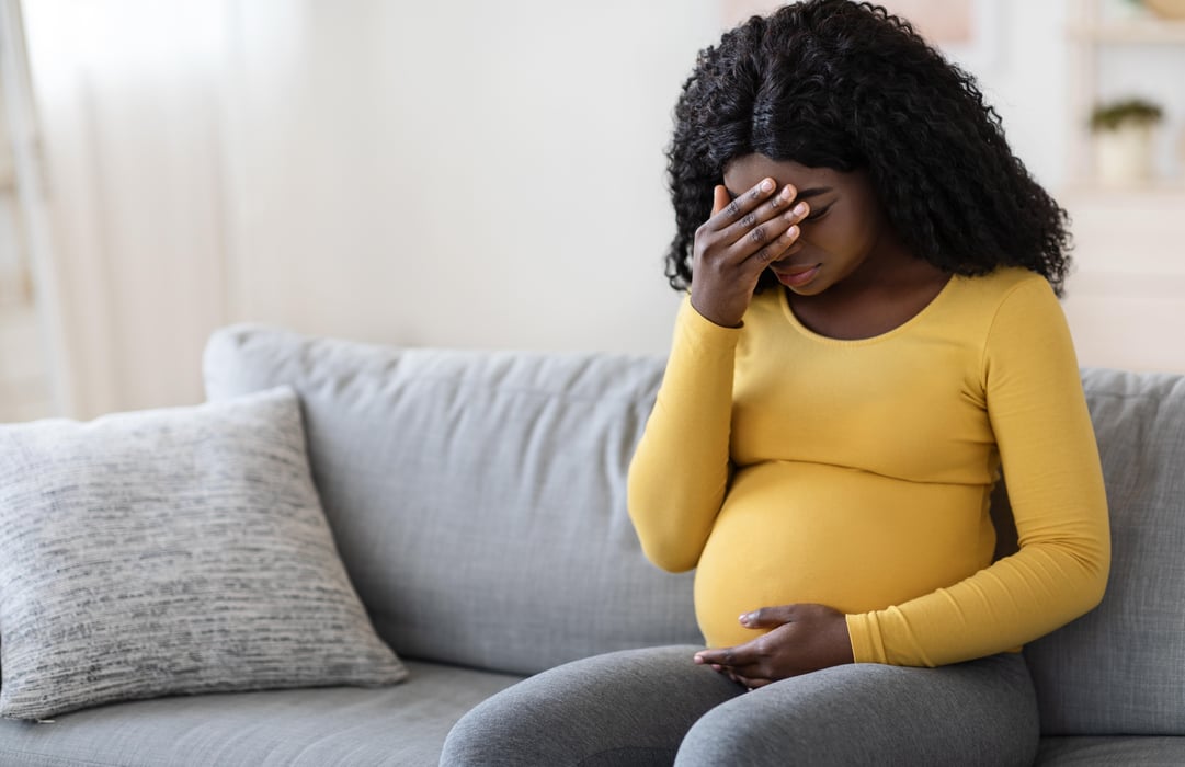 Black pregnant woman suffering from headache at home