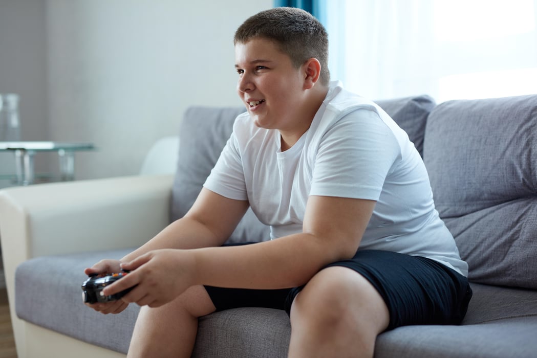 fat caucasian teenager boy enjoys video games