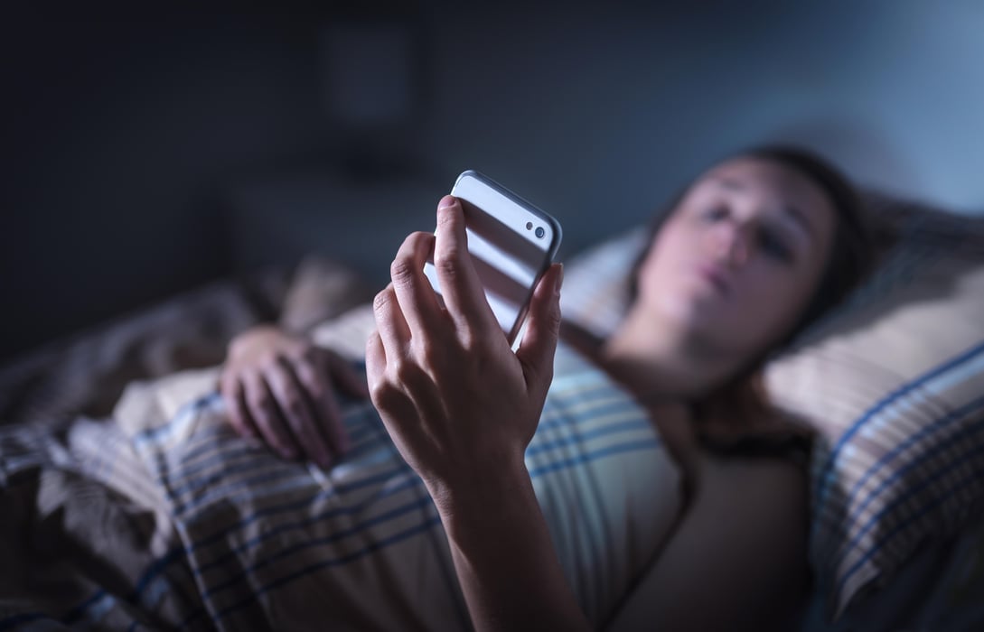 insomnia Sad upset woman looking at smartphone at night in bed. Phone call from unknown caller. Sleepless person suffering from stress or insomnia. Worried or lonely lady in dark home using cell, reading text.
