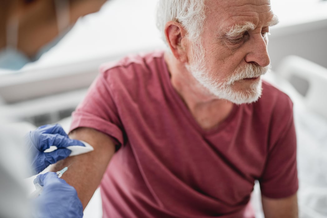 Old man receiving vaccine shot in hand