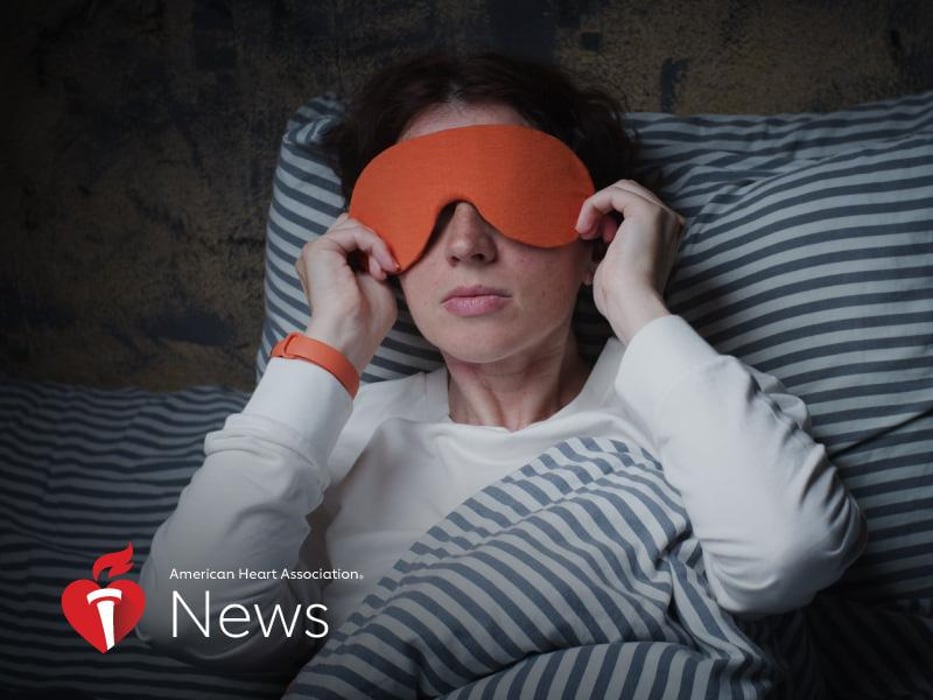 A woman wearing a sleeping face cover over her eyes laying in bed