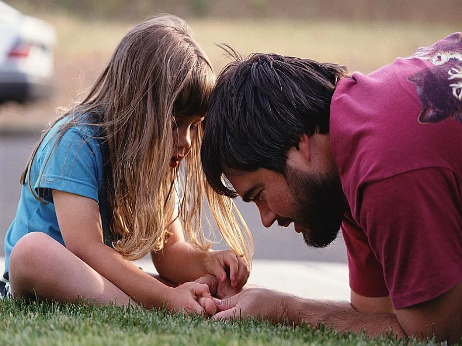man checking little girl\'s toe
