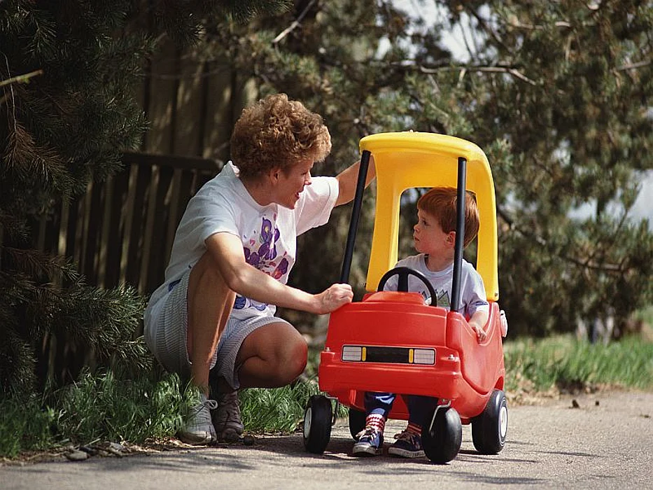 kid in a toy car with a caregiver