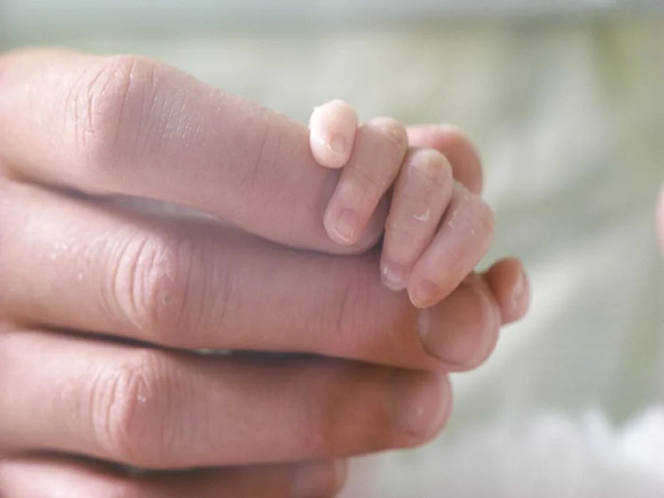 parent holding baby\'s hand