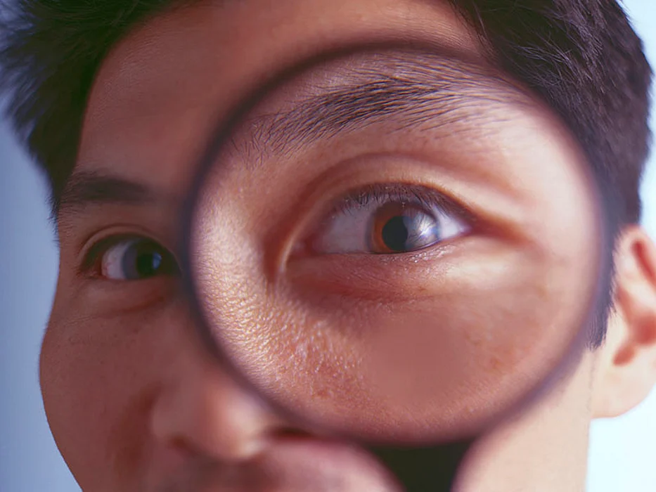 man looking through magnifying glass