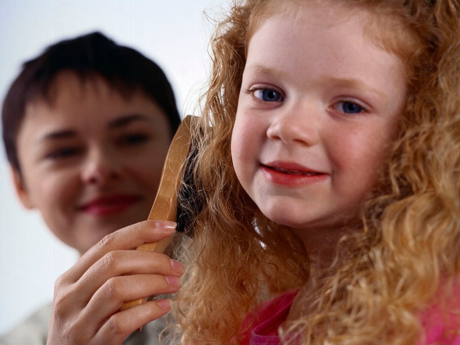 mother brushing daughter\'s hair