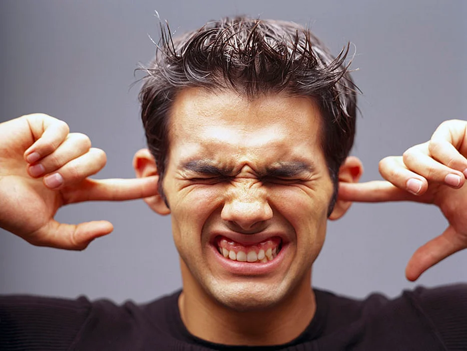 man plugging his ears