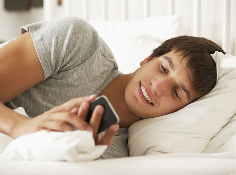 teen texting in bed