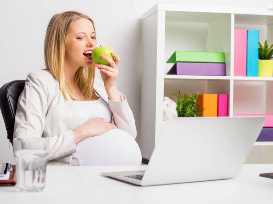 pregnant woman at work eating an apple