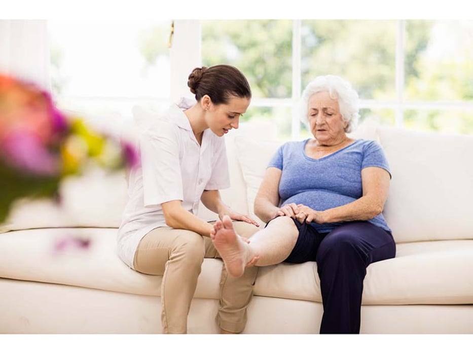 older woman showing her leg to a caregiver