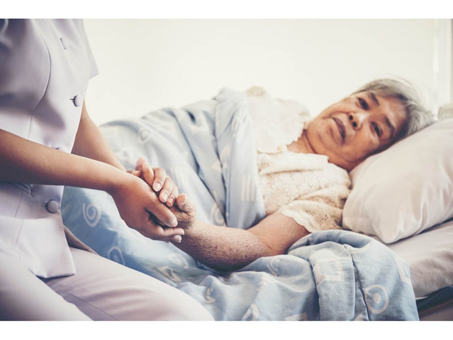 woman on a hospital bed holding a caregiver hand
