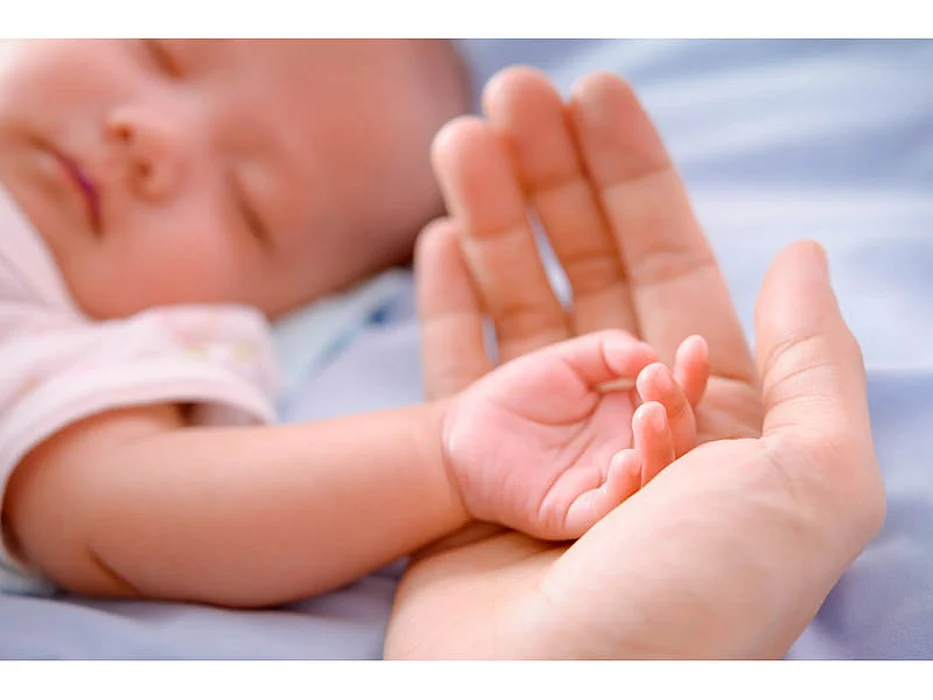 sleeping baby\'s hand inside an adult\'s