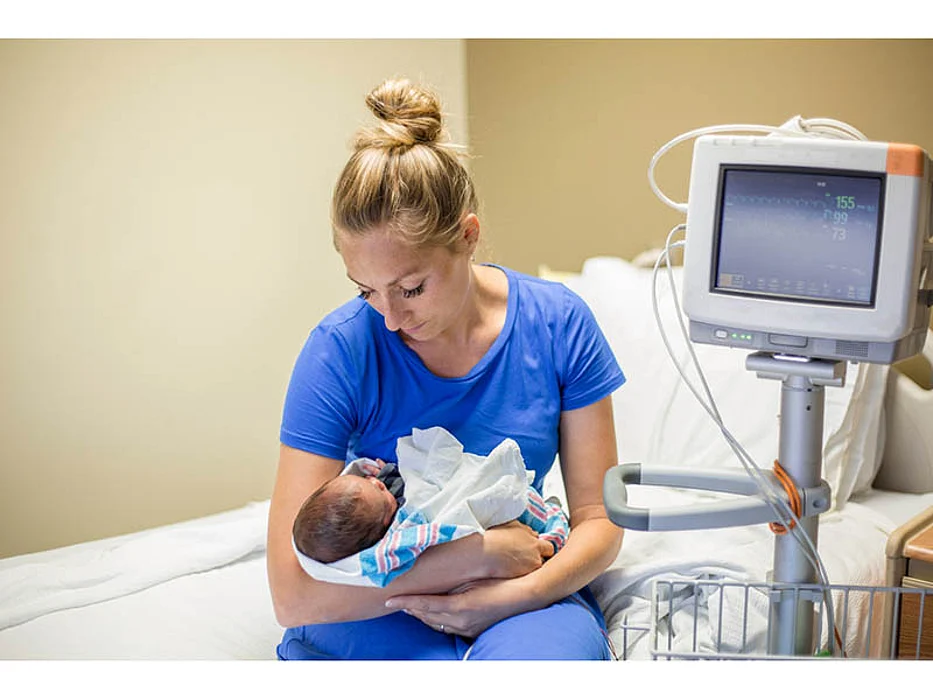 newborn in the arm of a woman in the hospital