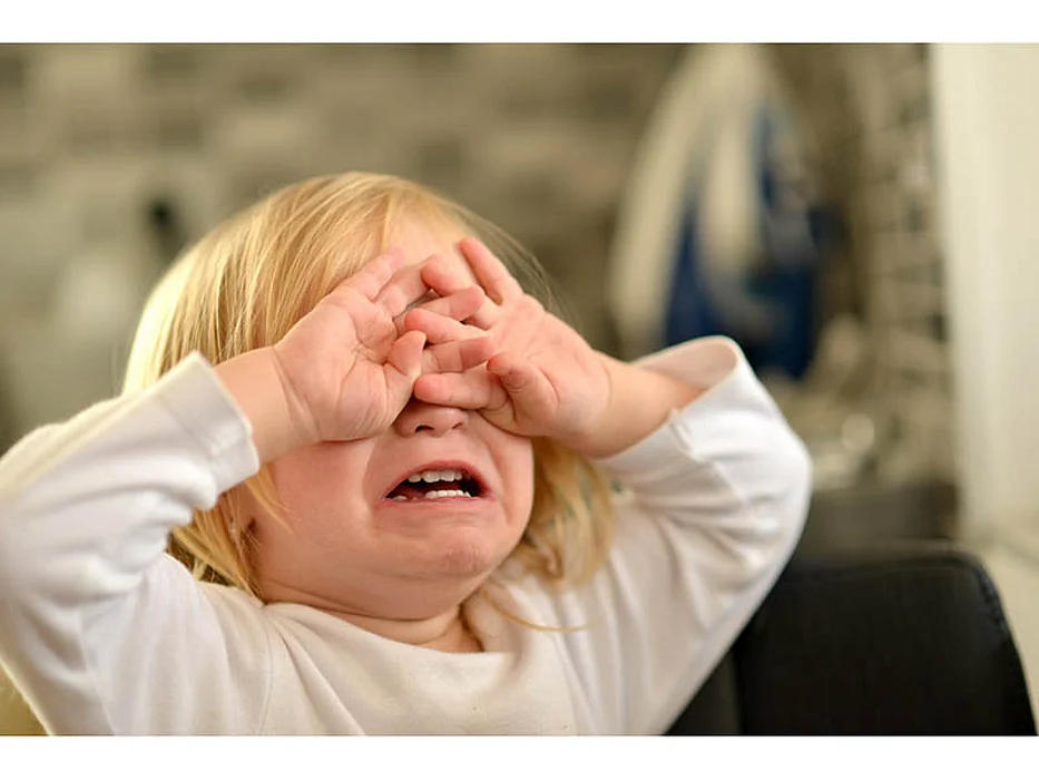 small child crying covering his eyes
