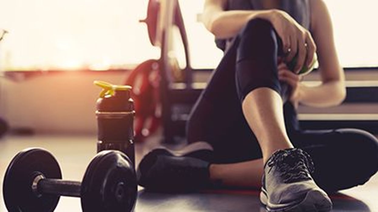 woman sitting on the gym floor with weights