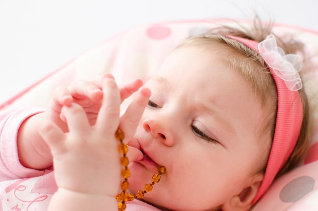 a baby chewing on a necklace