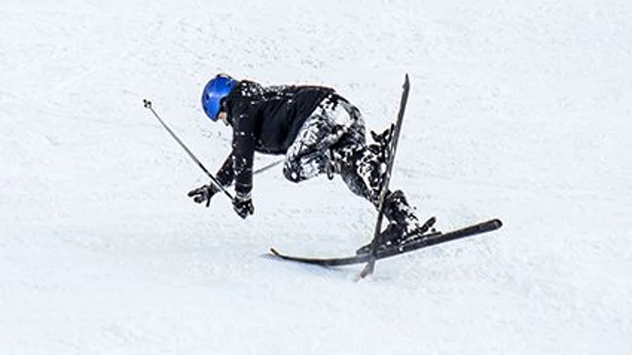 a boy falling on the skies on the slope