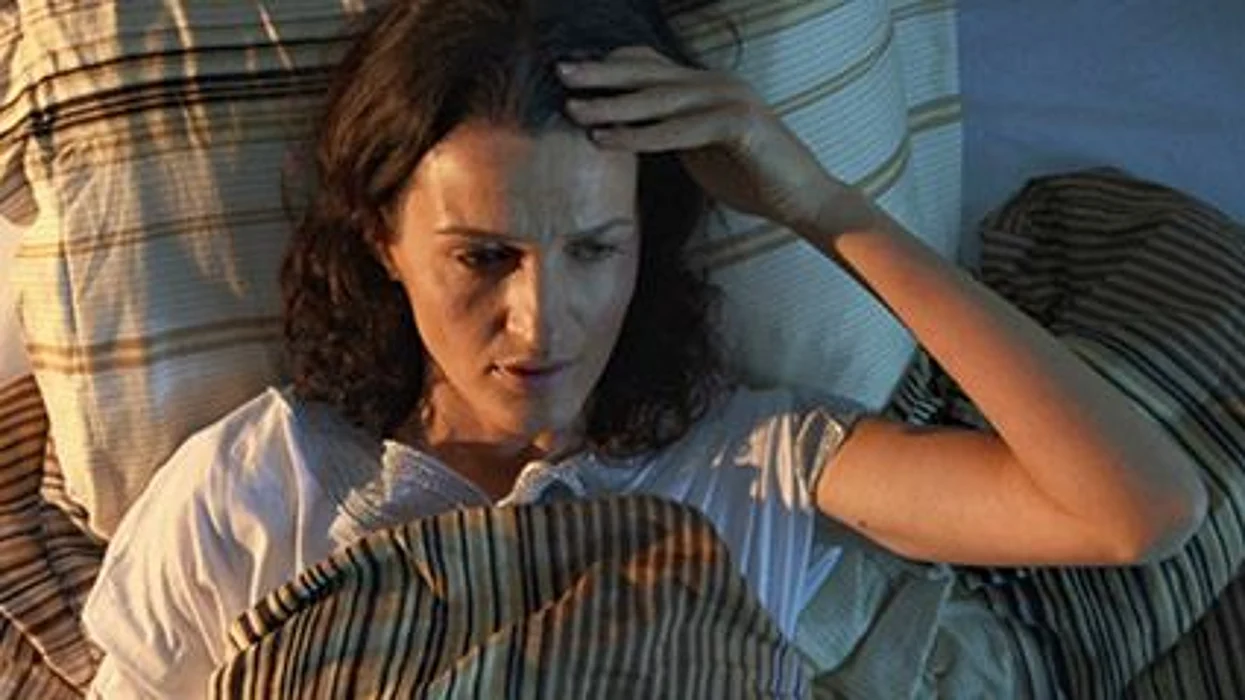 a woman in a bed holding her head