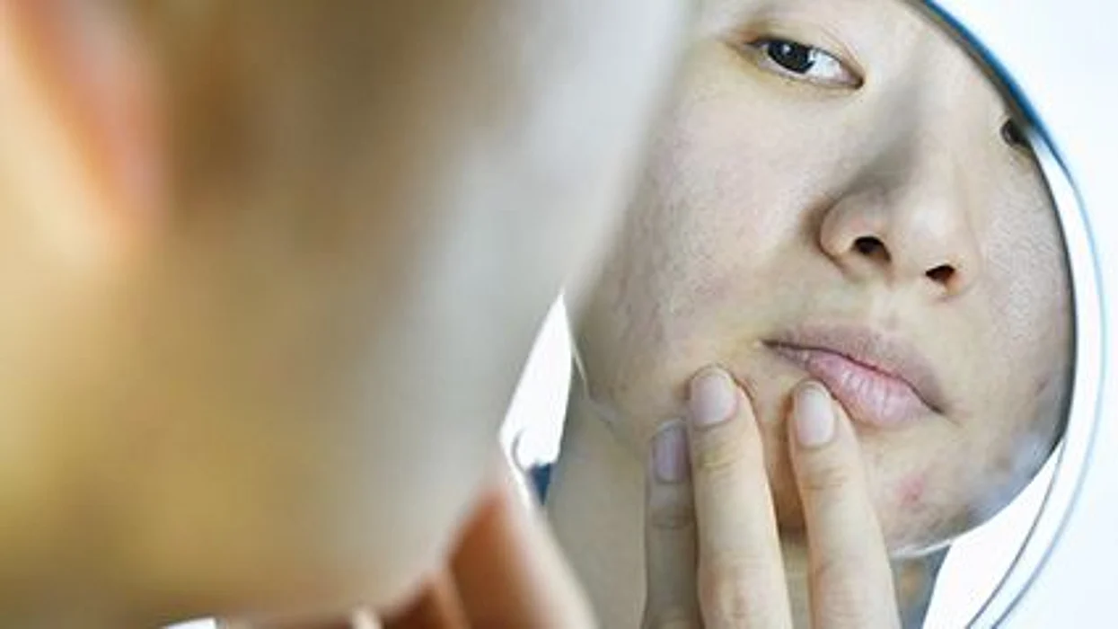 a person looking at her face in the mirror