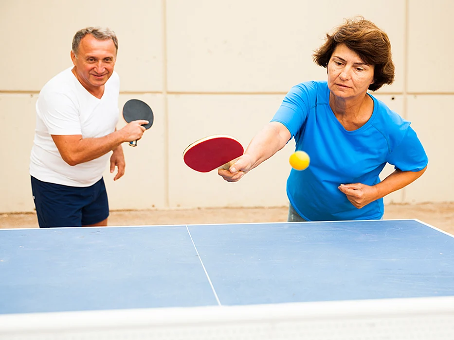 happy adults playing table ping pong