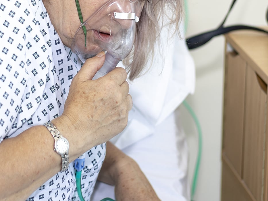 Woman in hospital with breathing difficulties using a respiration mask