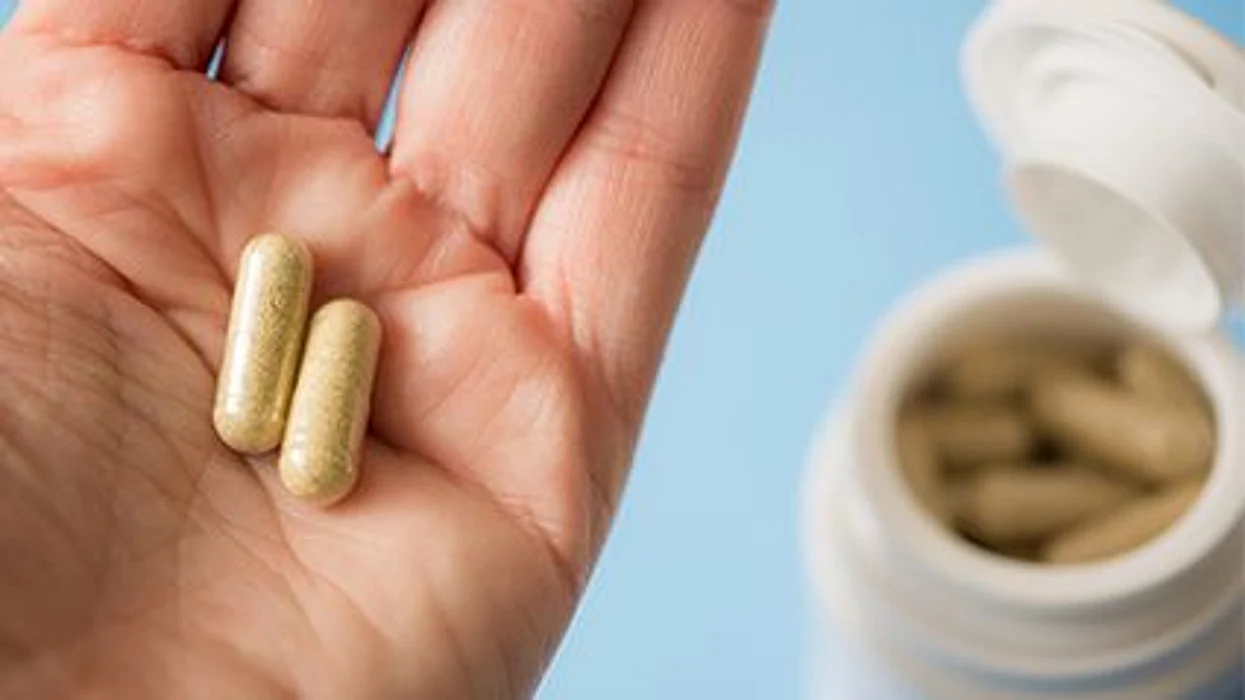 a person holding two pills on the hand