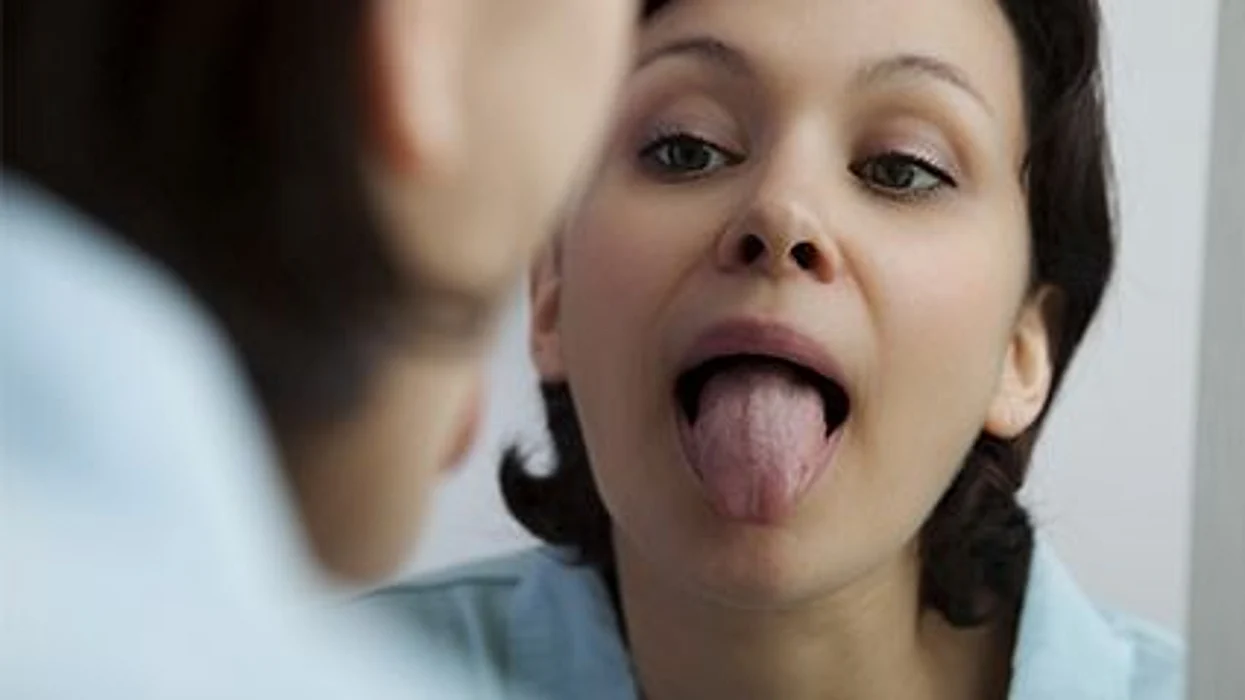 a woman looking at her tounge in the mirror
