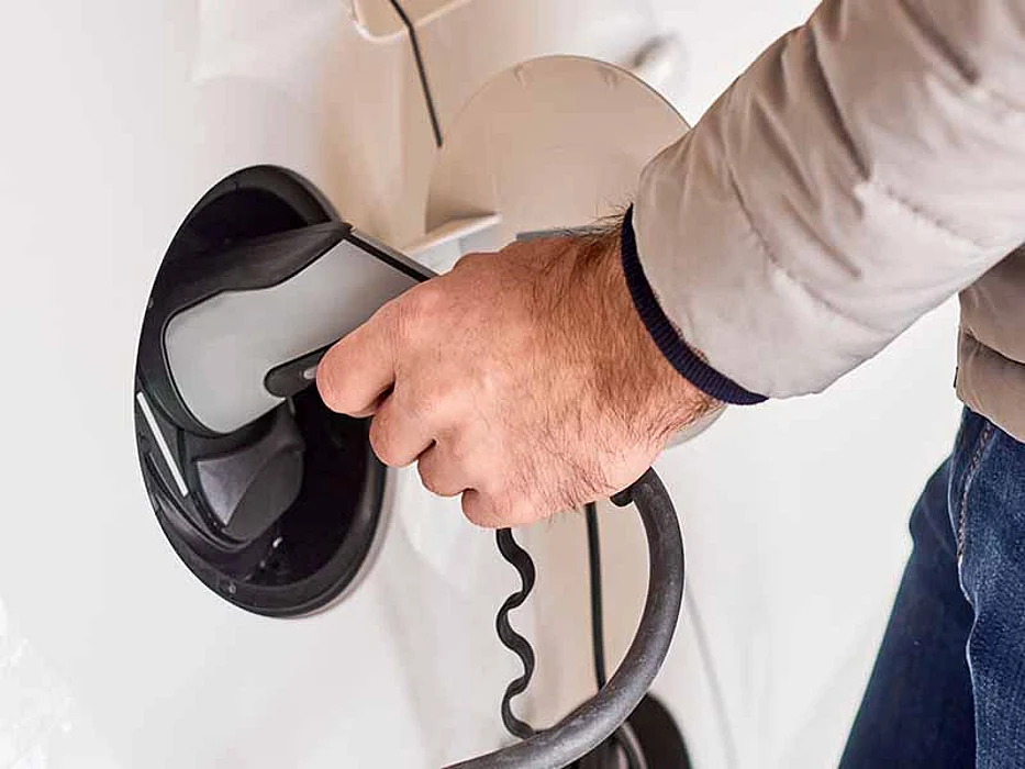 Close up mans hand holding a charger plug of an electric car