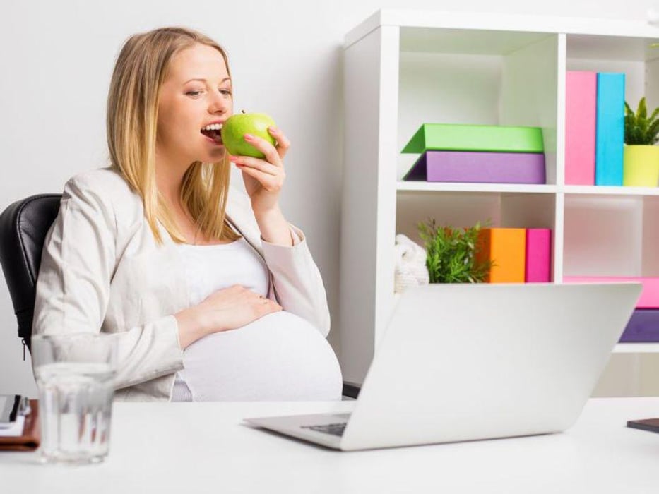 pregnant woman at work eating an apple