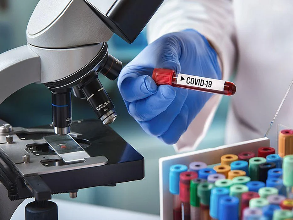 doctor in a lab with a blood tube labeled covid-19