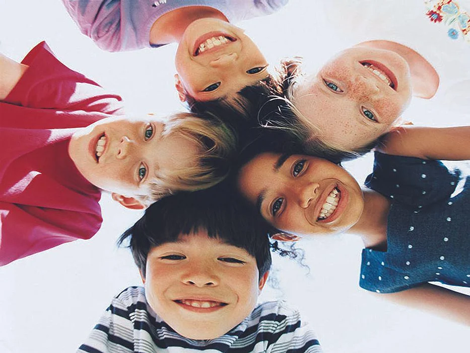five kids smiling with their heads placed together