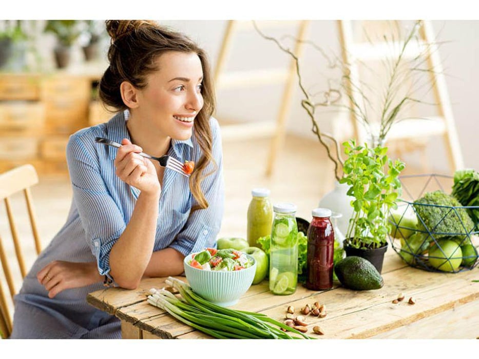 woman smiling and eating a healthy salad