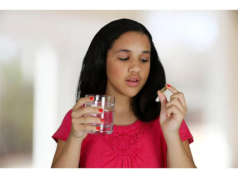 a girl ready to swallow her pill with glass of water
