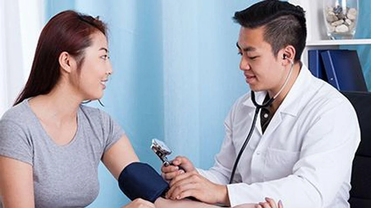 a doctor mesures patient\'s blood pressure