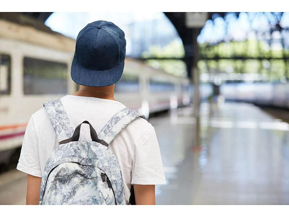 a back of a person with a backpack on the train station