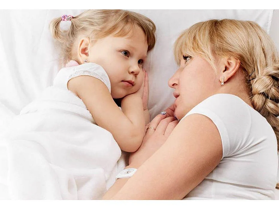 a girl lying on a bed with her mother
