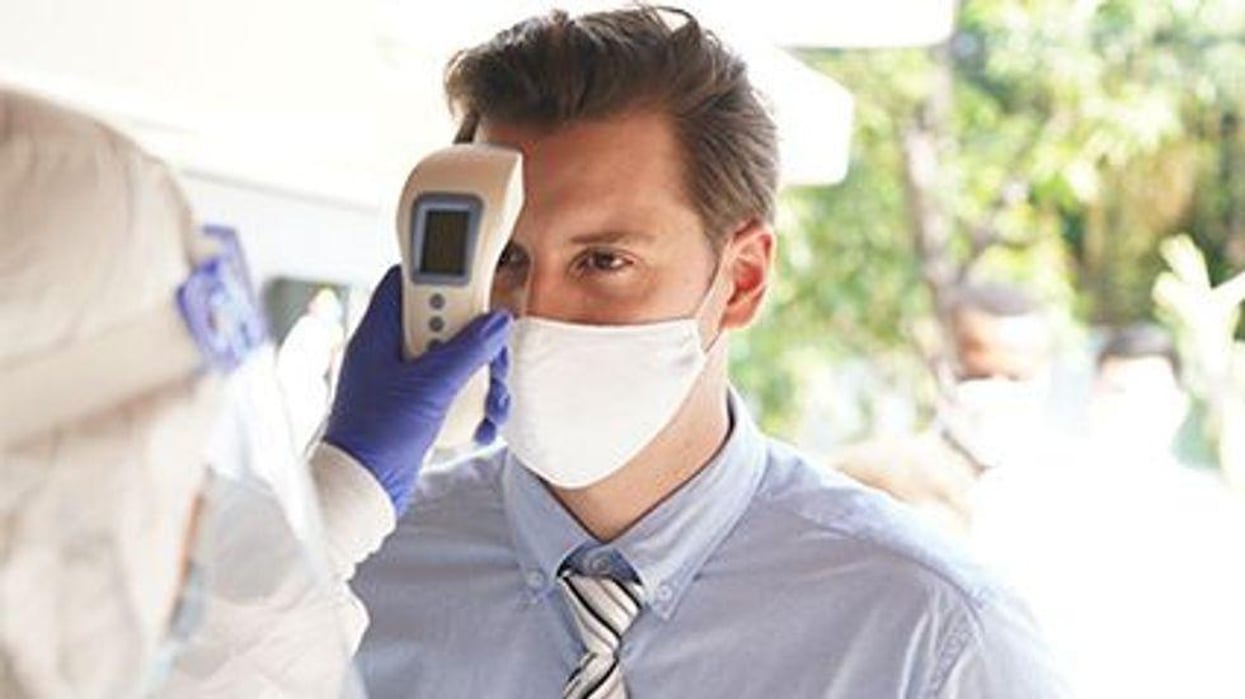 a person with a mask on being checked for his temperature