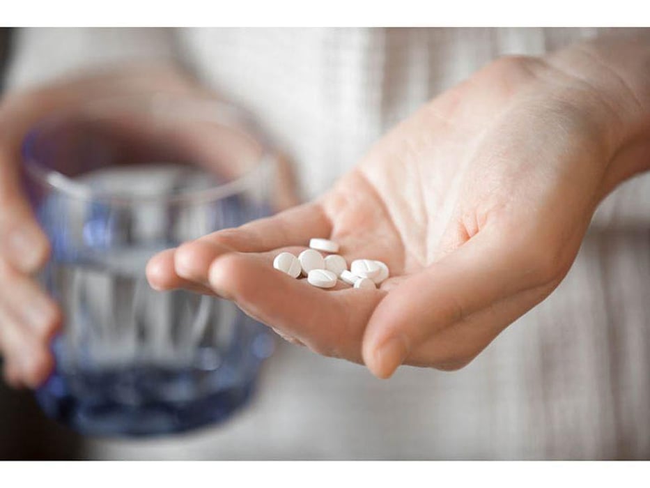a person holding pills on the palm of her hand