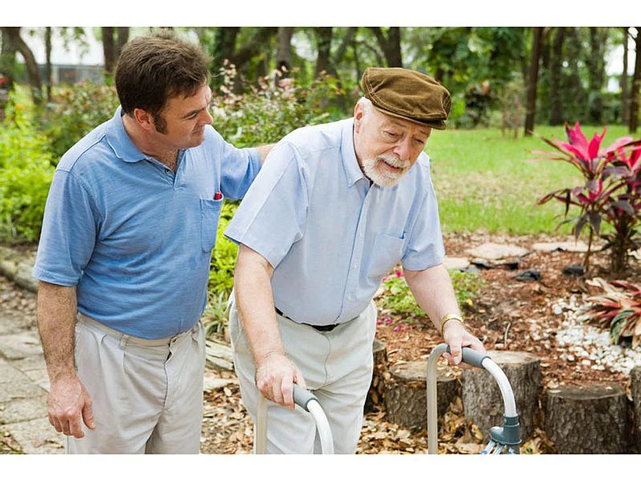 older man walking with a walker and younger man by his side