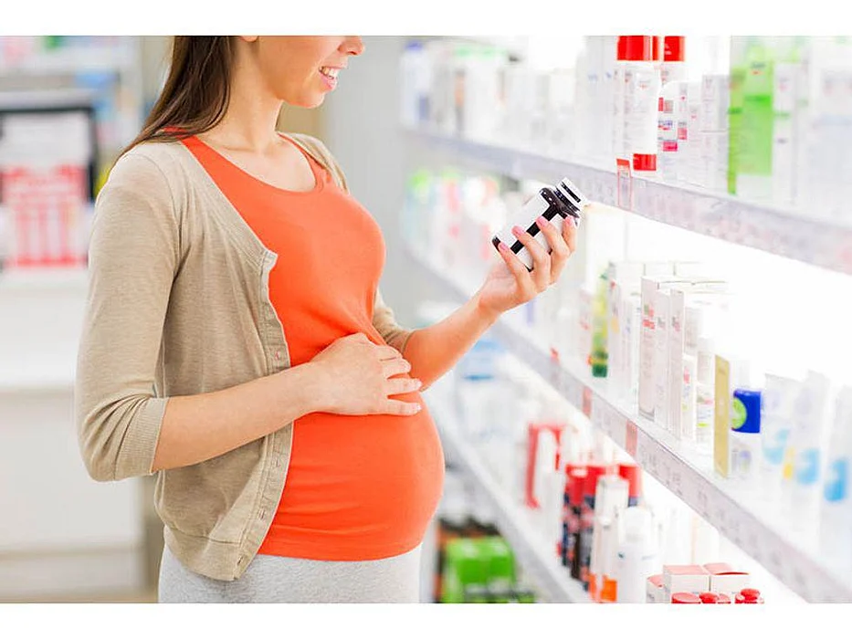 pregnant woman looking at the medicine bottle