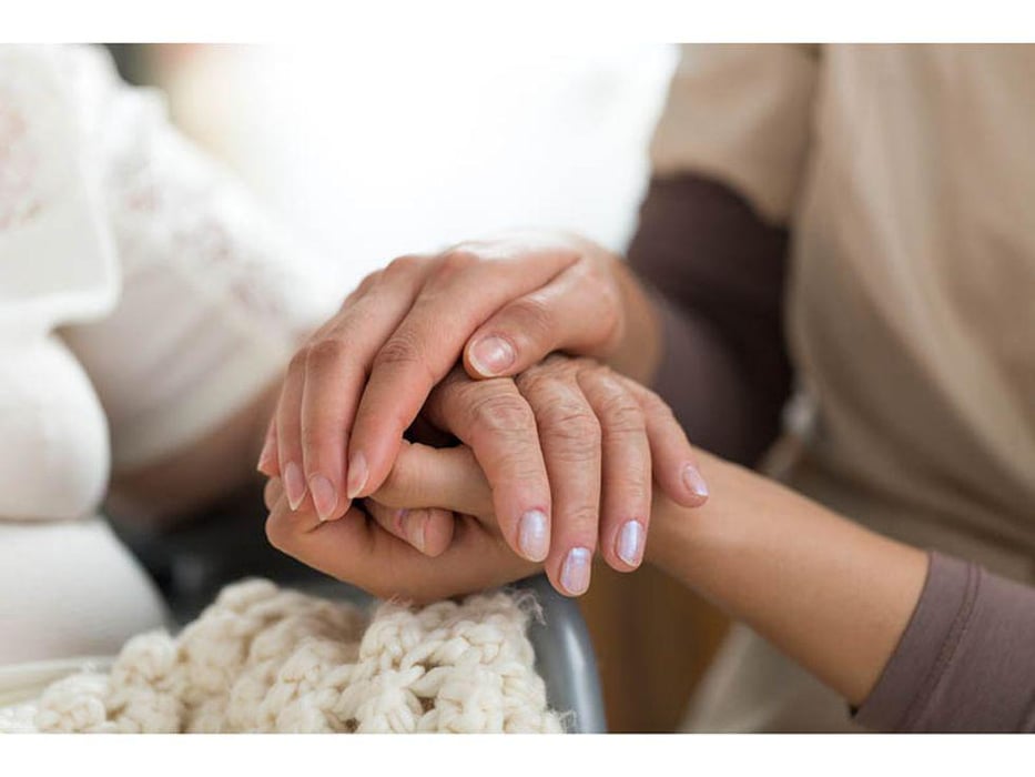 woman holding hand of woman she is caring for